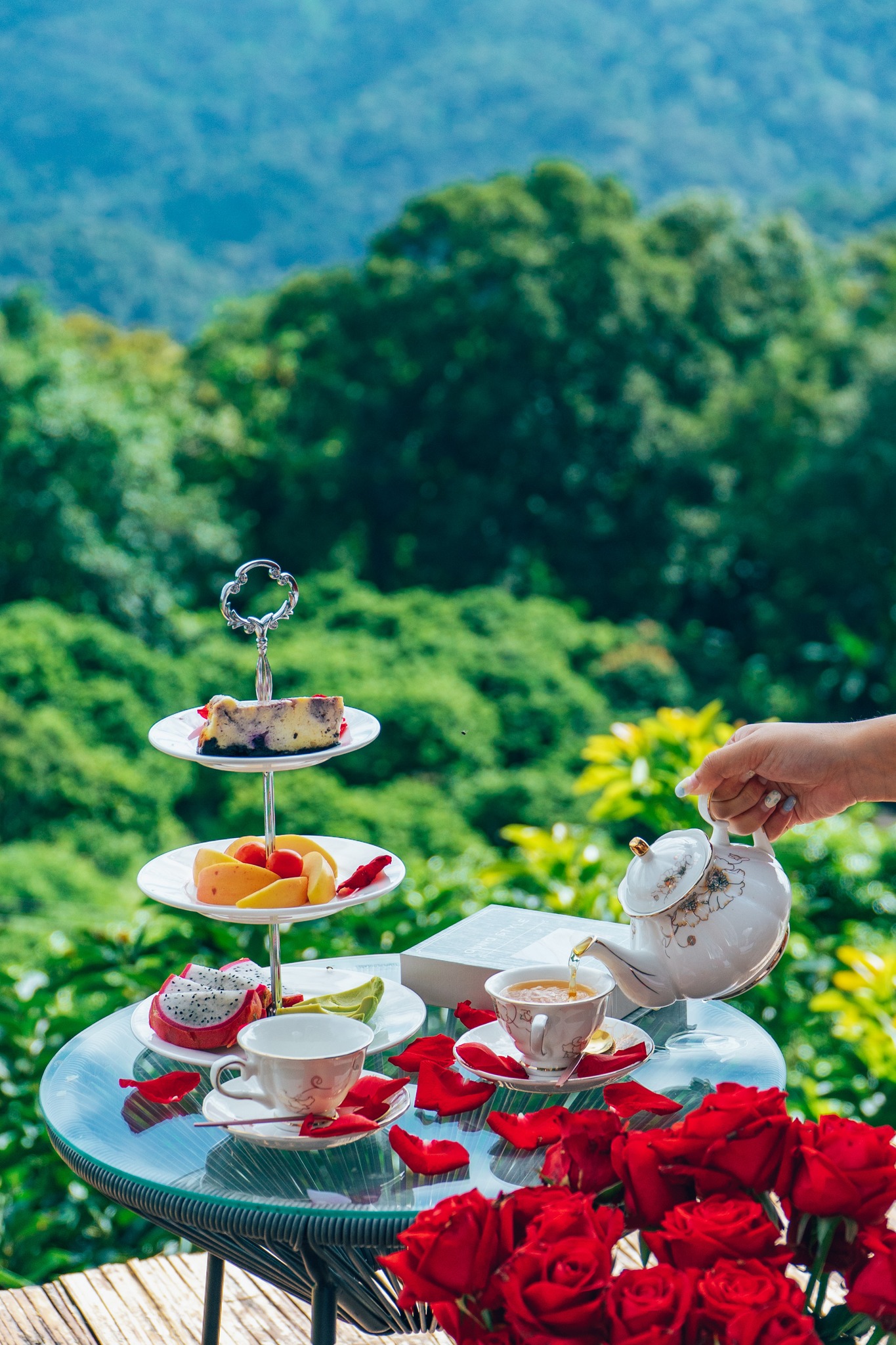 A steaming Mookata (Thai BBQ) set is placed on a table on the cabin's balcony, with the mountain view in the background.